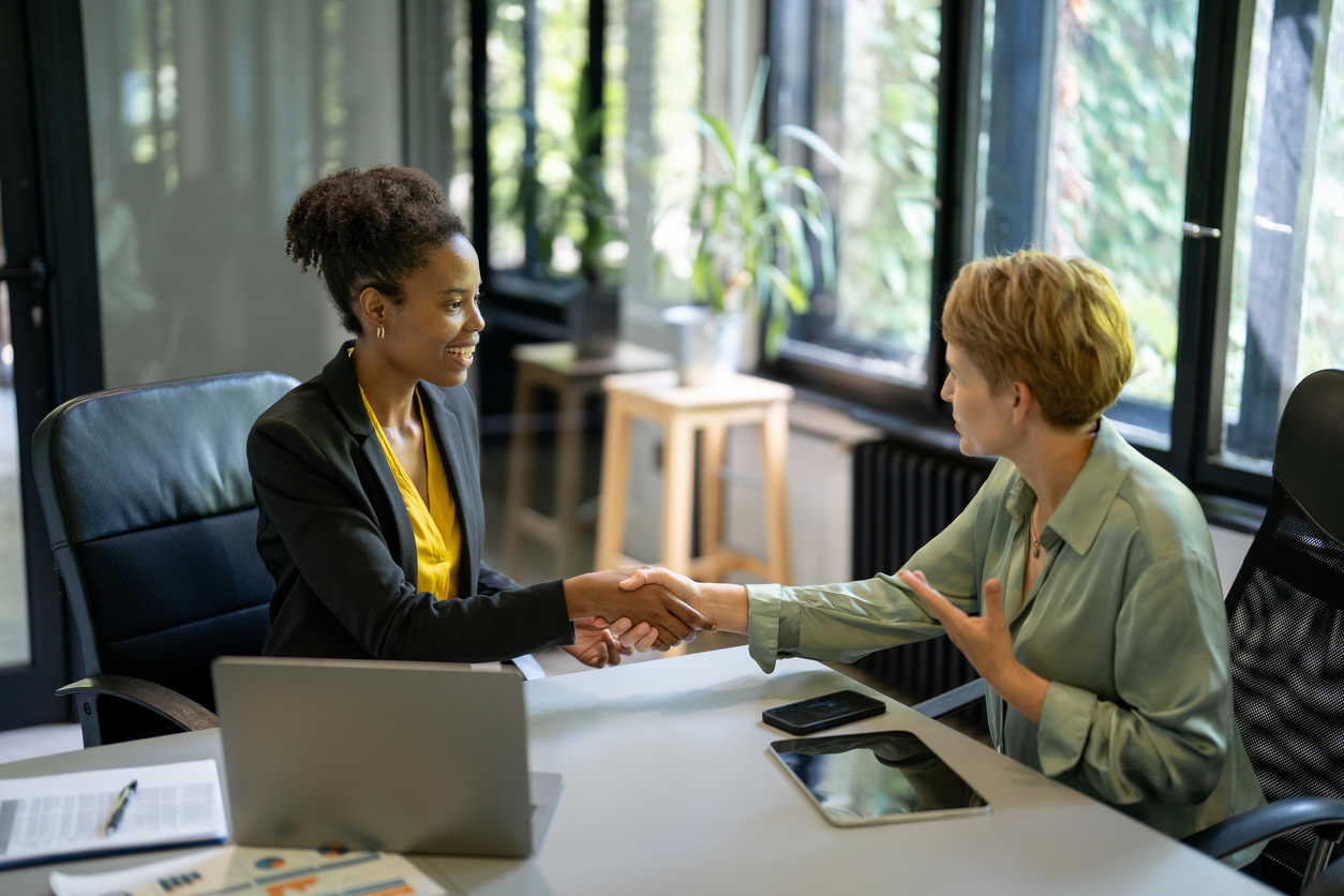 An HR manager shakes hands with a job applicant to begin an interview.