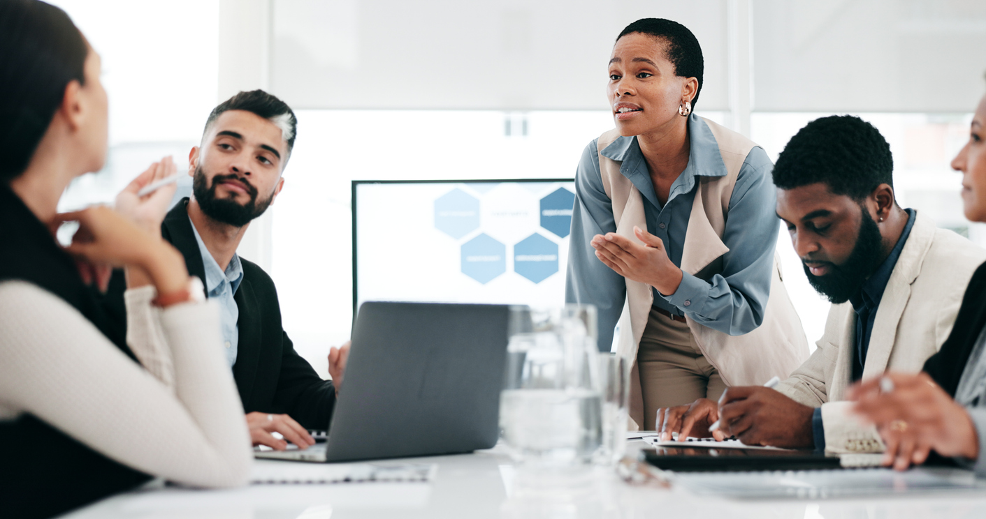 A group of businesspeople meet around a conference table.